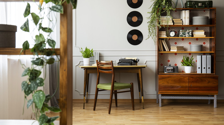 A home office with oak floors, a small wooden desk in a slightly darker tone, a mid-century modern wooden chair and an even darker tone, and a refurbished wooden bookcase
