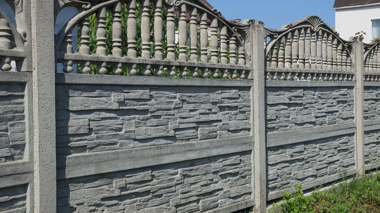 A decorative stone fence between two residential backyards.