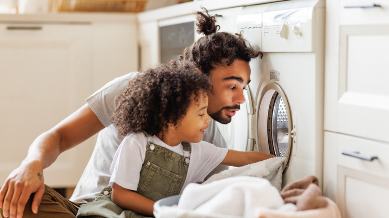 A man and his daughter loading a washing machine