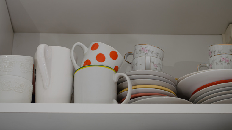 Coffee mugs stacked high in a cabinet.