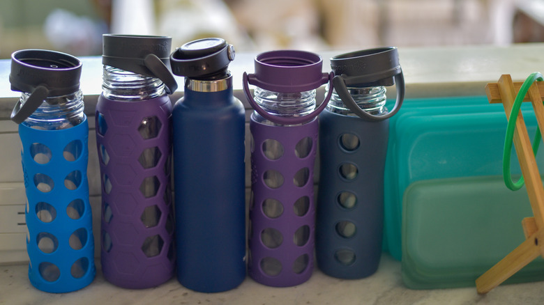 Five reusable water bottles on countertop.