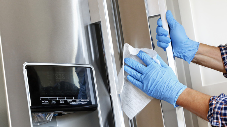 person with gloves cleaning fridge 