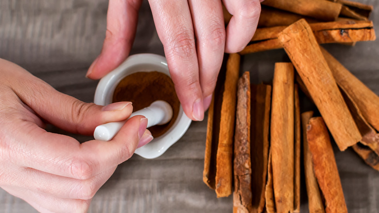 Grinding cinnamon in a pestle and mortar