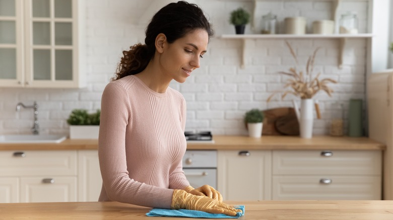 woman cleaning wood kitchen countertop