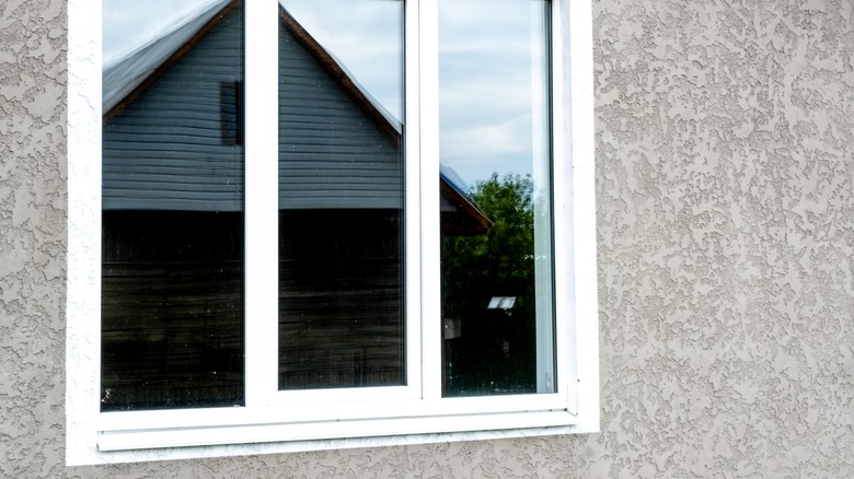 A house with white window and gray stucco siding.
