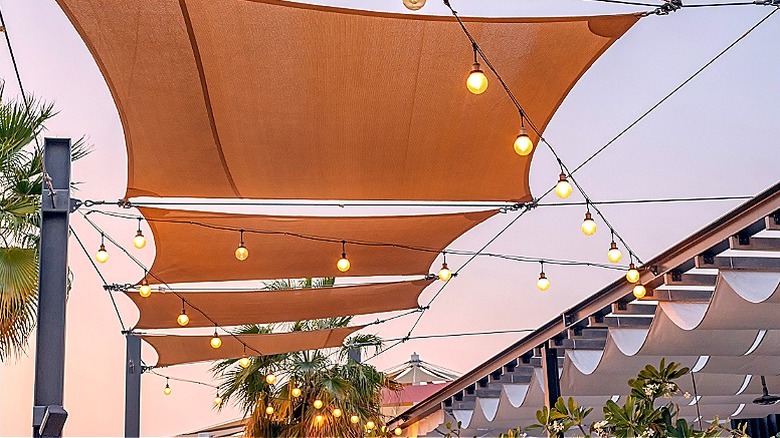 Shade sails hang outdoors above stringed lights.
