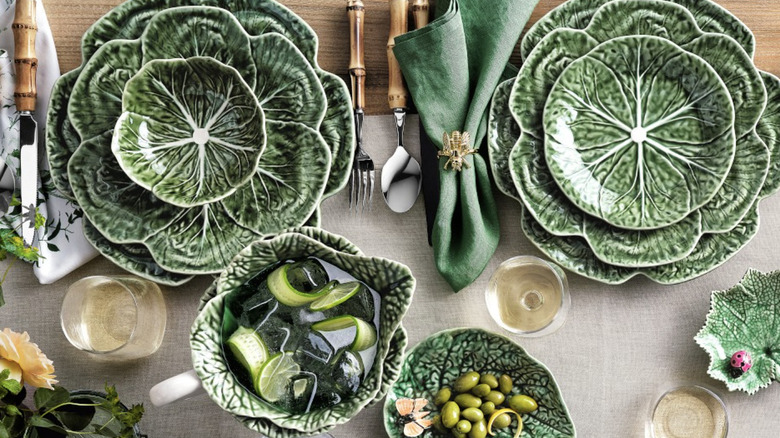 Product image of Bordallo Pinheiro cabbage plates and matching kitchenware spread out on a table