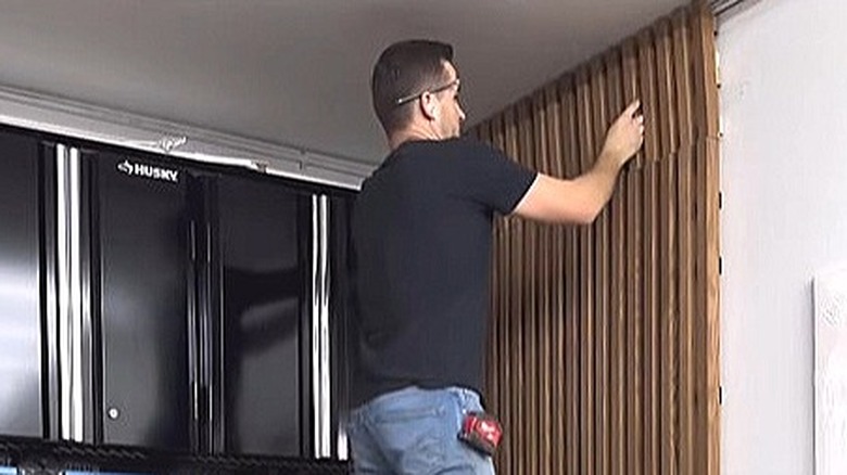 A man installing wooden panels to conceal a water heater.