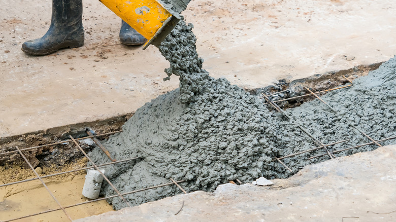 Concrete being poured into a hole with wires for support from a machine