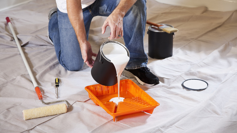 person pouring paint into tray