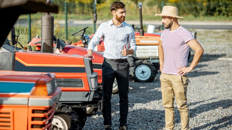 Two people discussing different farm tractors