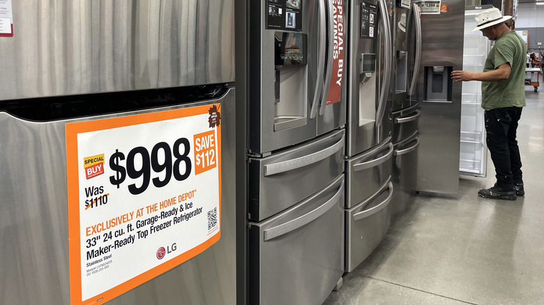 Gray refrigerators on display in a store, with a man looking at one.