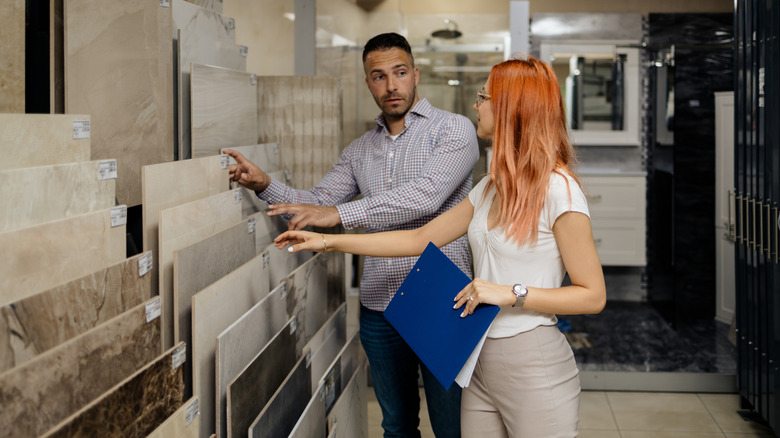 A man and a woman shopping for tile options and looking at samples in a store