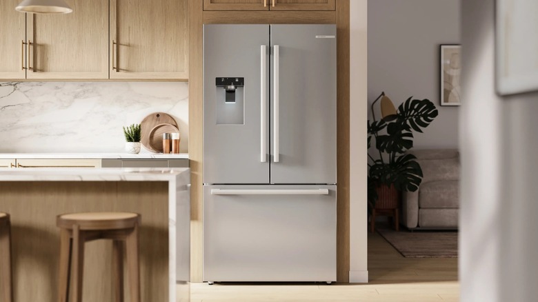 A stainless-steel Bosch French-door refrigerator is in a kitchen surrounded by light wood cabinets.