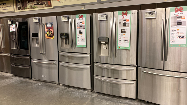 Several French-door refrigerators stand in a line inside a home improvement store.