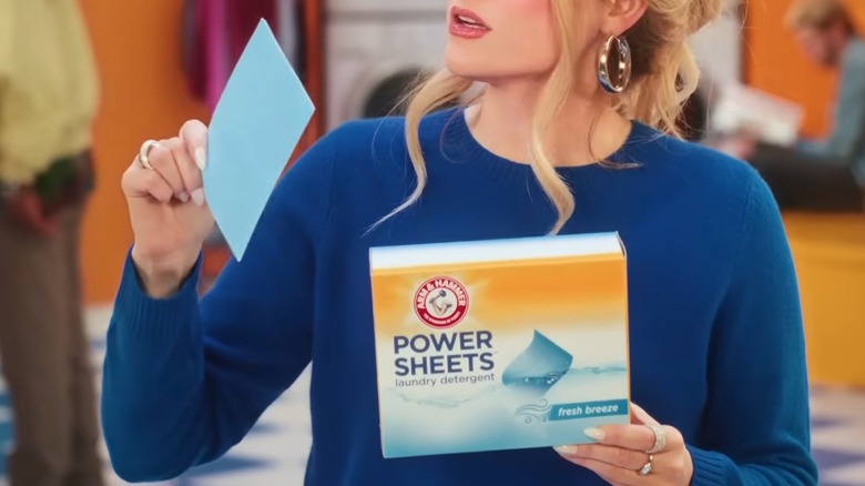 A female is holding a sheet and a box of Arm and Hammer Laundry Sheets