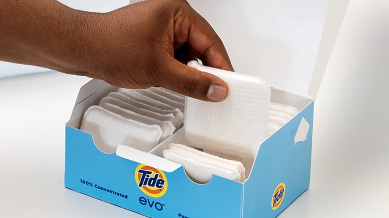 Hand picking out a thick laundry tile from a pack of Tide Evo