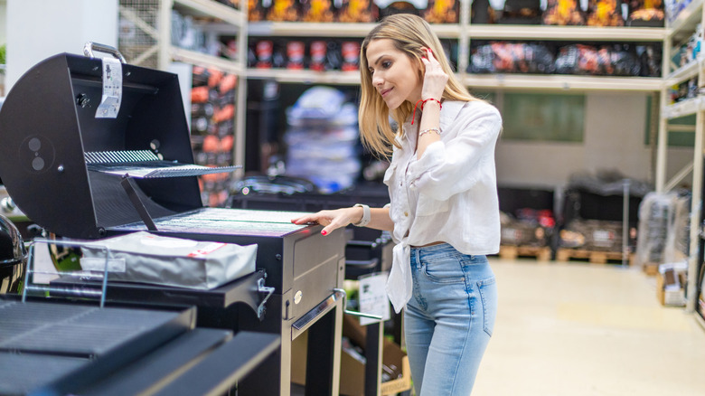 Woman selecting a new barbecue grill in a hardware store