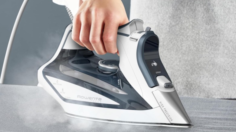 A hand irons cloth with a Rowenta steam iron.