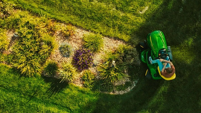 Person using a John Deere X354 riding lawn tractor