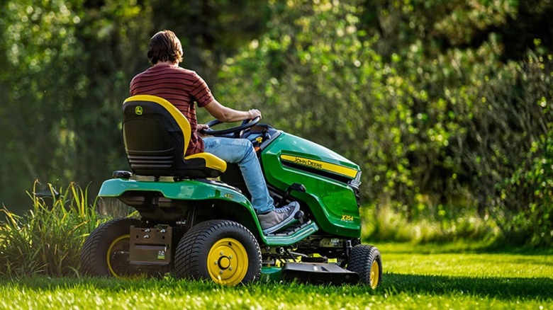 Person using a John Deere X354 riding lawn tractor