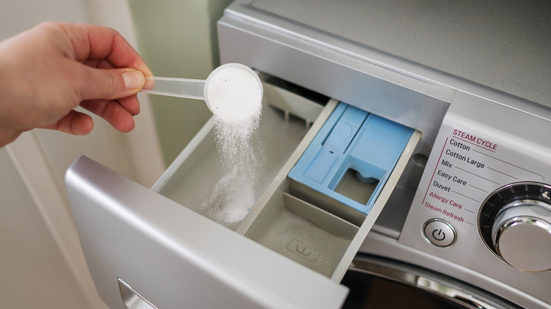 Pouring powdered laundry detergent into the detergent tray for a washer.