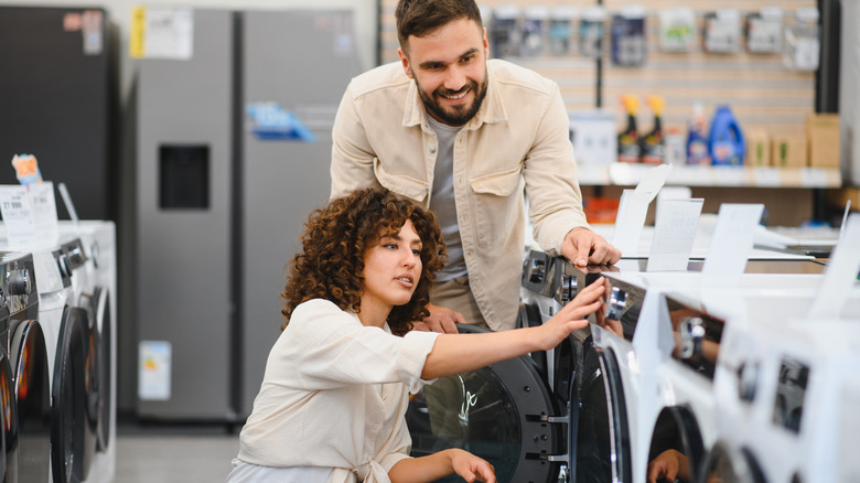 Couple evaluating a washing machine at an appliance store