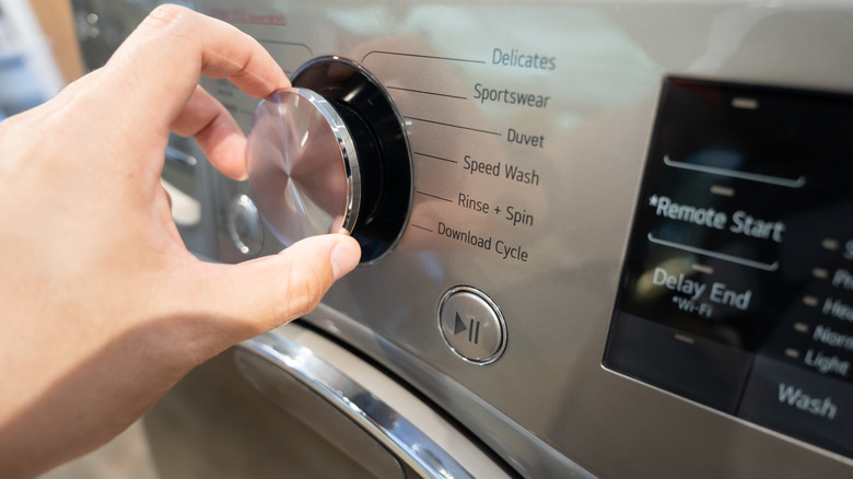 Close-up of a hand adjusting the settings on a washing machine