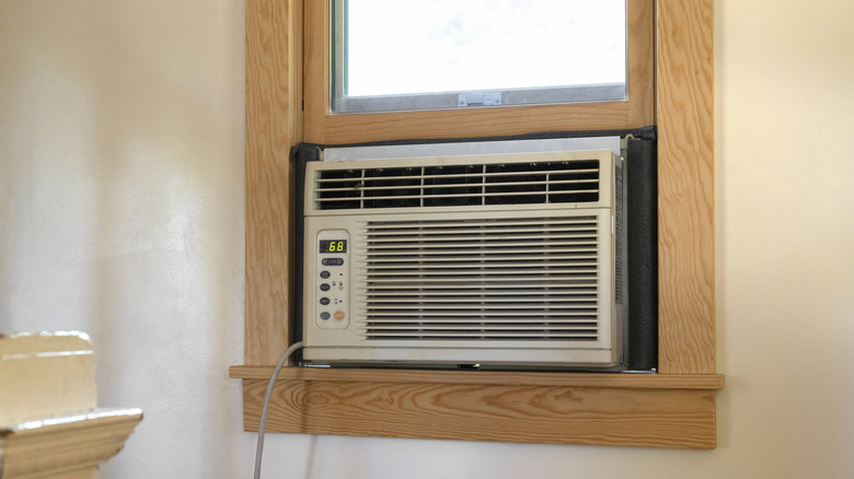 AC unit installed in a window with light brown wood frame surrounding it