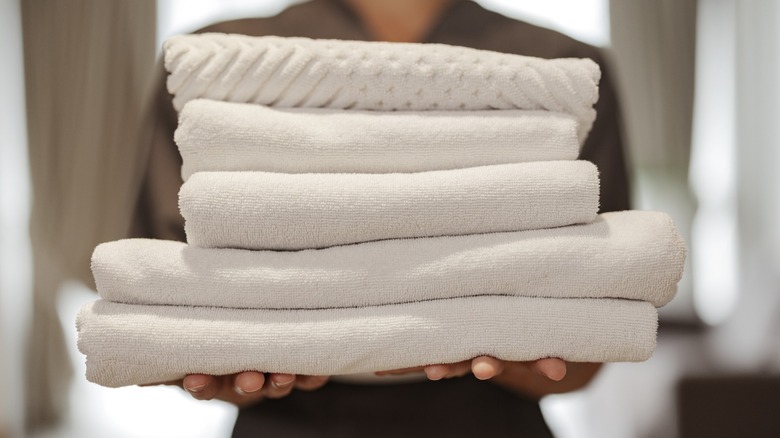 a woman holds several folded towels