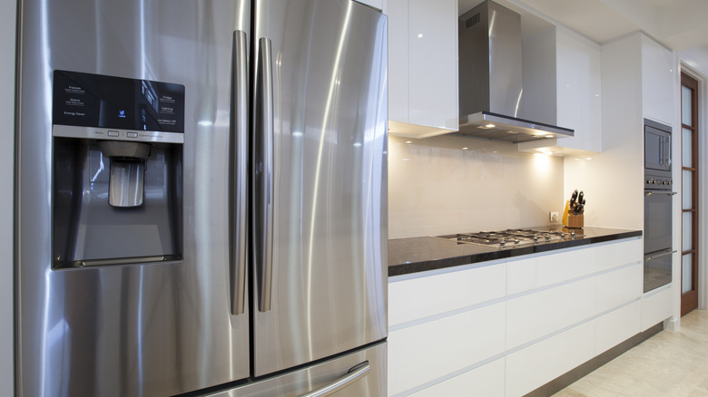A kitchen at an angle with a focus on the stainless steal, double-doored fridge closest to the camera