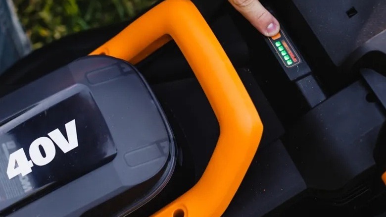 Person checking the battery level on a Worx mower