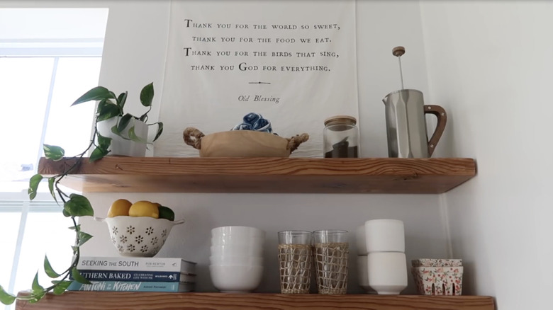 Floating wood shelves styled with dishware, cookbooks, and plants.