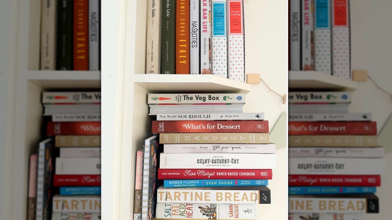 Stack of cookbooks on a small corner shelf.