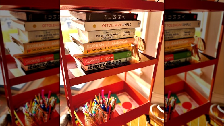 A red kitchen trolley filled with cookbooks.