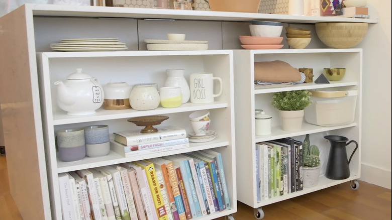 Shelves tucked under a kitchen breakfast bar, styled with books and mugs.