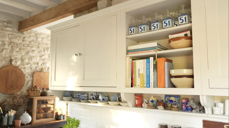 An open shelf displaying cookbooks and dishware.