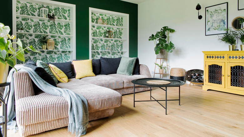A living room with a corduroy sofa and green walls
