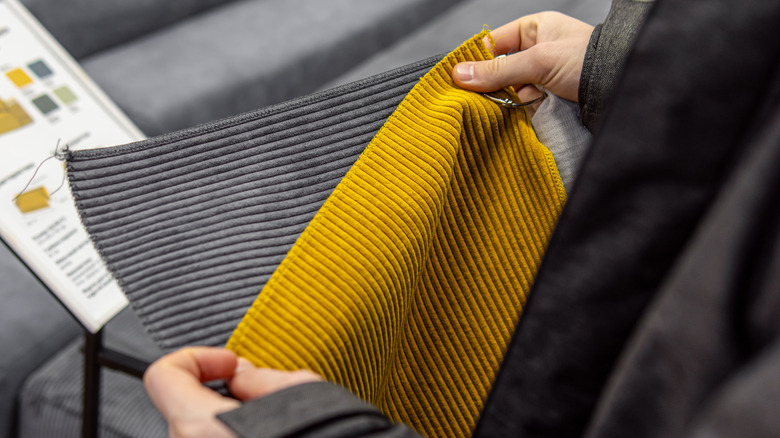 Person holding yellow and gray corduroy fabric samples