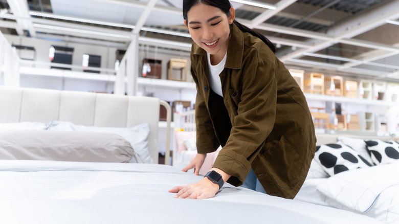 A woman feeling a mattress at the store