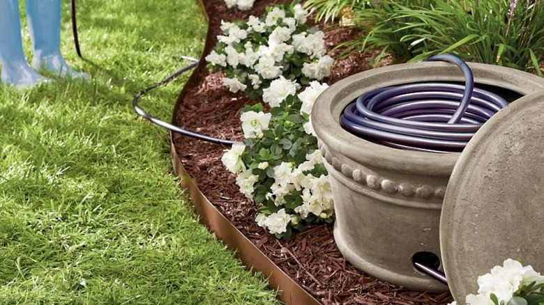 Grandin road beaded hose pot placed in garden bed with hose