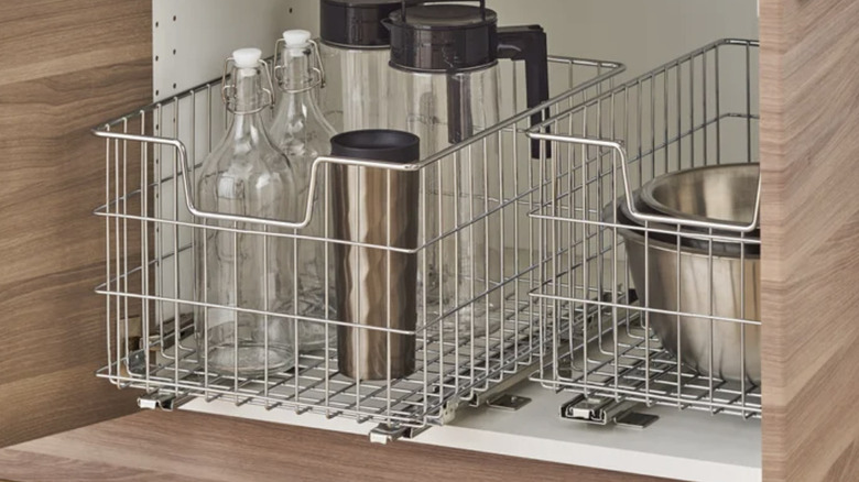 Wire baskets in kitchen cabinets, holding mixing bowls and glass bottles
