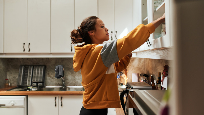 Woman putting items away in kitchen cabinets