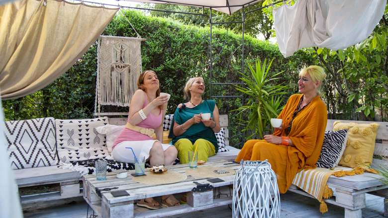 Three women laughing in the shade of a gazebo