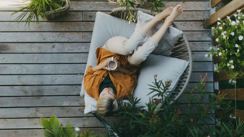 Person relaxing on patio with a cup of coffee in a comfy chair