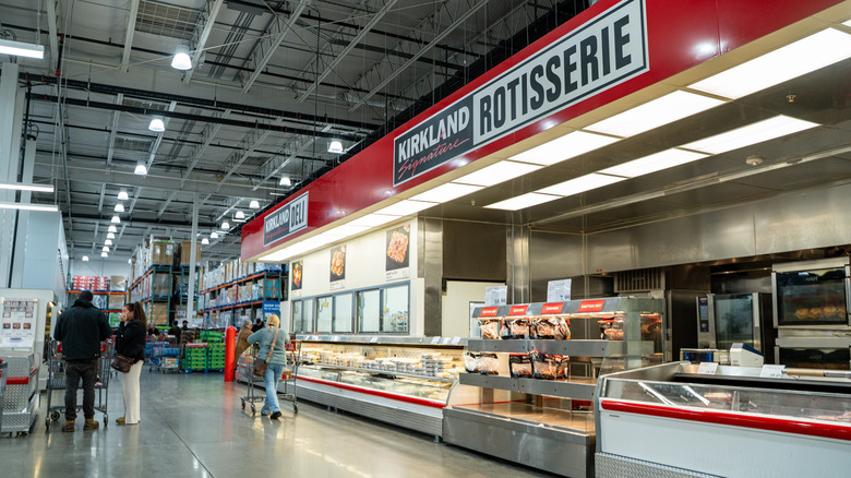 Peopl walking in Costco in front of the Kirkland rotisserie section