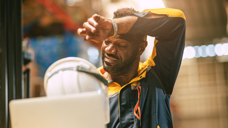 Warehouse worker wiping forehead