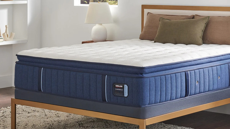 Blue and white Kirkland mattress on a bed frame with no sheets