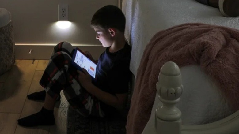 Boy reading a tablet near an LED outlet cover
