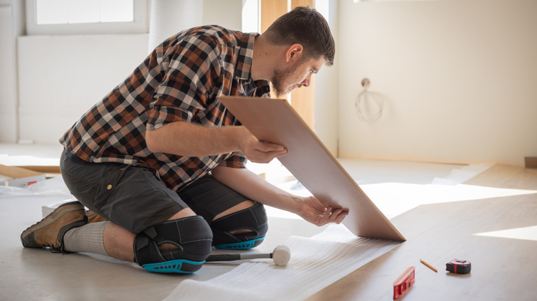 Man installing plank flooring in a home.